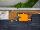 mise en oeuvre d'un revetement spécifique par des collaborateurs et un engin orange