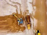 Vue aérienne d'une pelle mécanique chargeant du sable dans un tombereau lors des travaux de rééquilibrage de la plage de Houlgate.