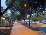 Promenade arborée éclairée au crépuscule avec espaces paysagers et bancs à Bordeaux.