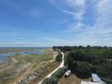 Vue aérienne d’un sentier côtier aménagé entre le bord de mer et un espace boisé.