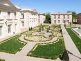 Vue panoramique des jardins à la française du Puy du Fou, avec parterres géométriques, pelouses, topiaires et bâtiments en pierre claire.